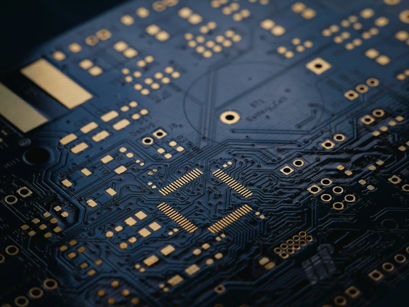Close-up of a dark blue printed circuit board with gold traces